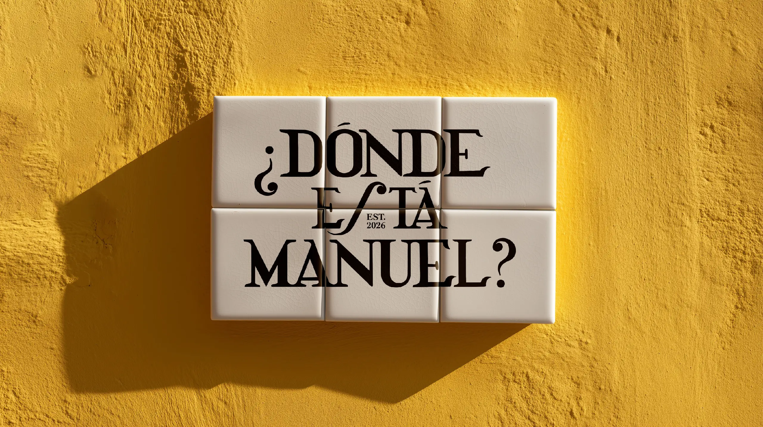 Azulejos blancos con el texto «¿Dónde está Manuel? Est. 2026» sobre una pared de estuco amarillo.